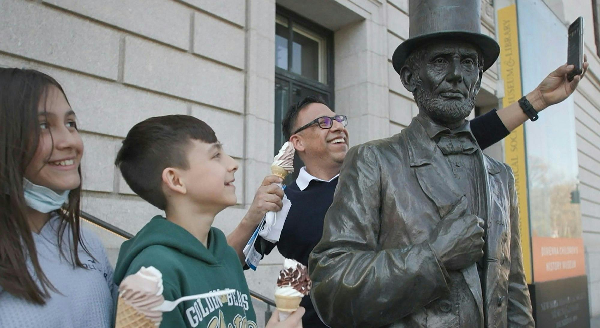 an adult and two kids taking a selfie at the Abraham Lincoln statue outside the museum